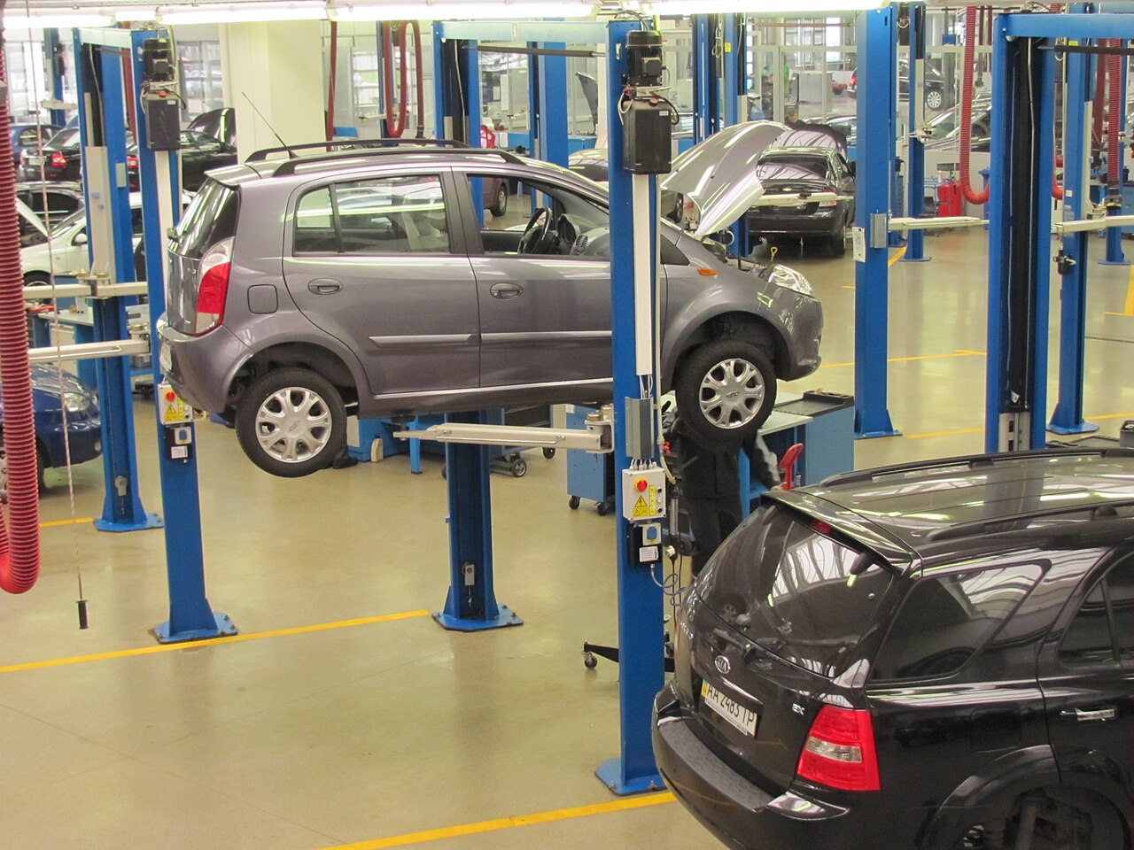 Several cars in a service workshop with vehicle lifts and repair bays.