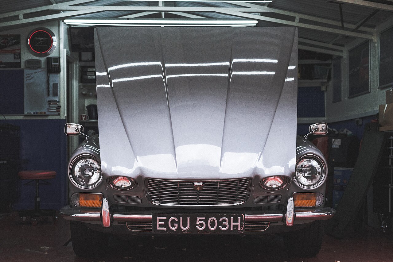 A classic car parked in a workshop with its hood open